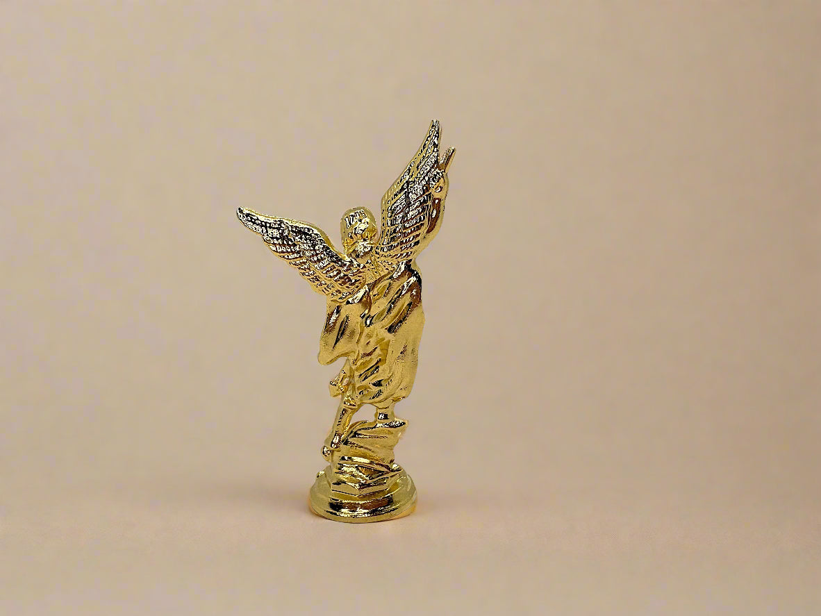 Back view of small gold colored Saint Michael Figurine on light gold background