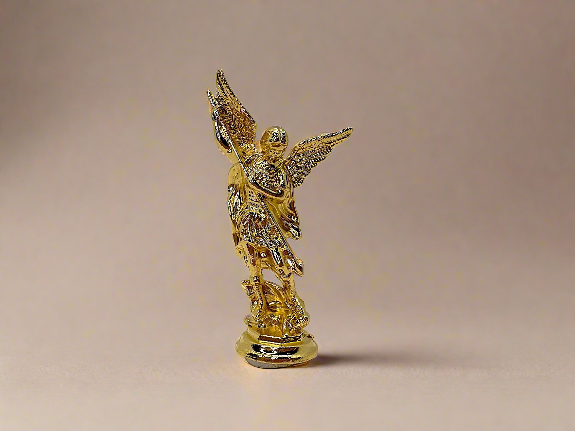 Front view of small gold colored Saint Michael Figurine on light gold background