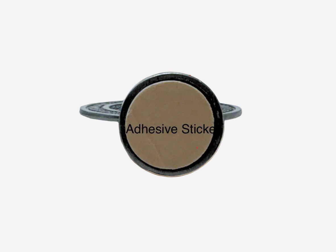 Dashboard St Benedict Medal in silver bottom view with round adhesive sticker with a beige center and black text on a white background