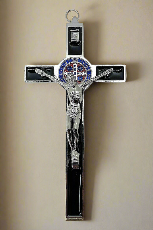 Decorative St. Benedict Crucifix with Black Enamel, blue, red and silver St. Benedict medal, silver corpus Cristi with silver and blue details on a beige wall background