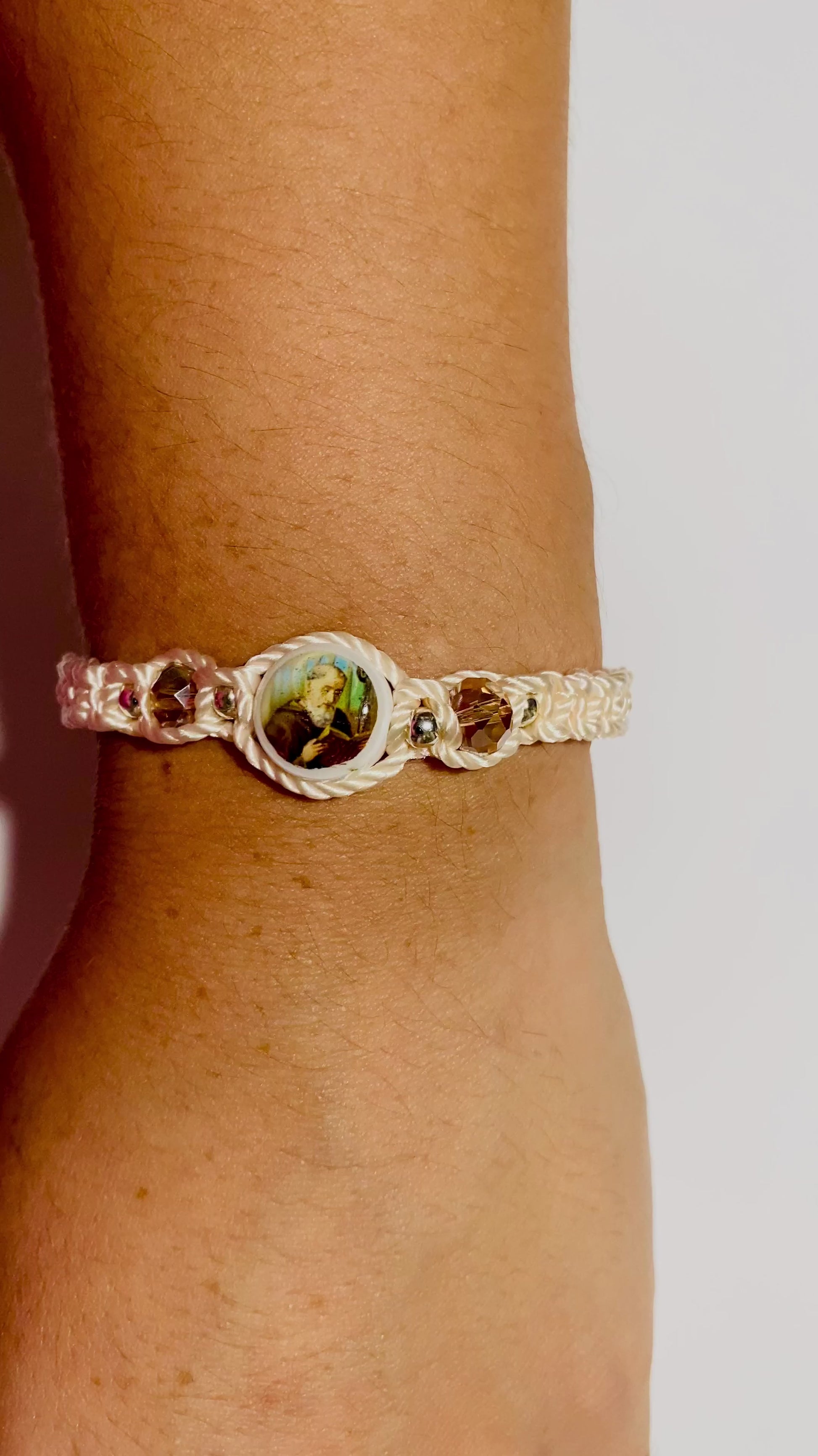 Close-up video of a hand wearing a beige  St. Benedict bracelet with sparkling crystal beads.