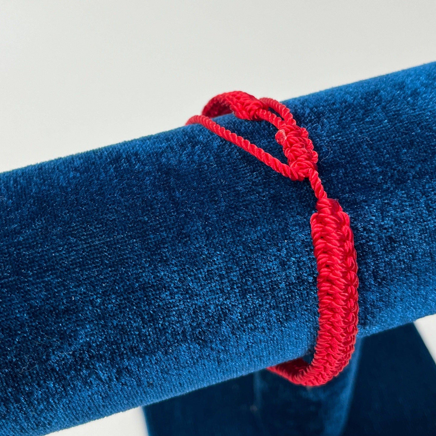 Back view of a adjustable Catholic bracelet in blue nylon thread featuring rhinestones, silver beads, and Guadalupe charm on a blue bracelet holder.
