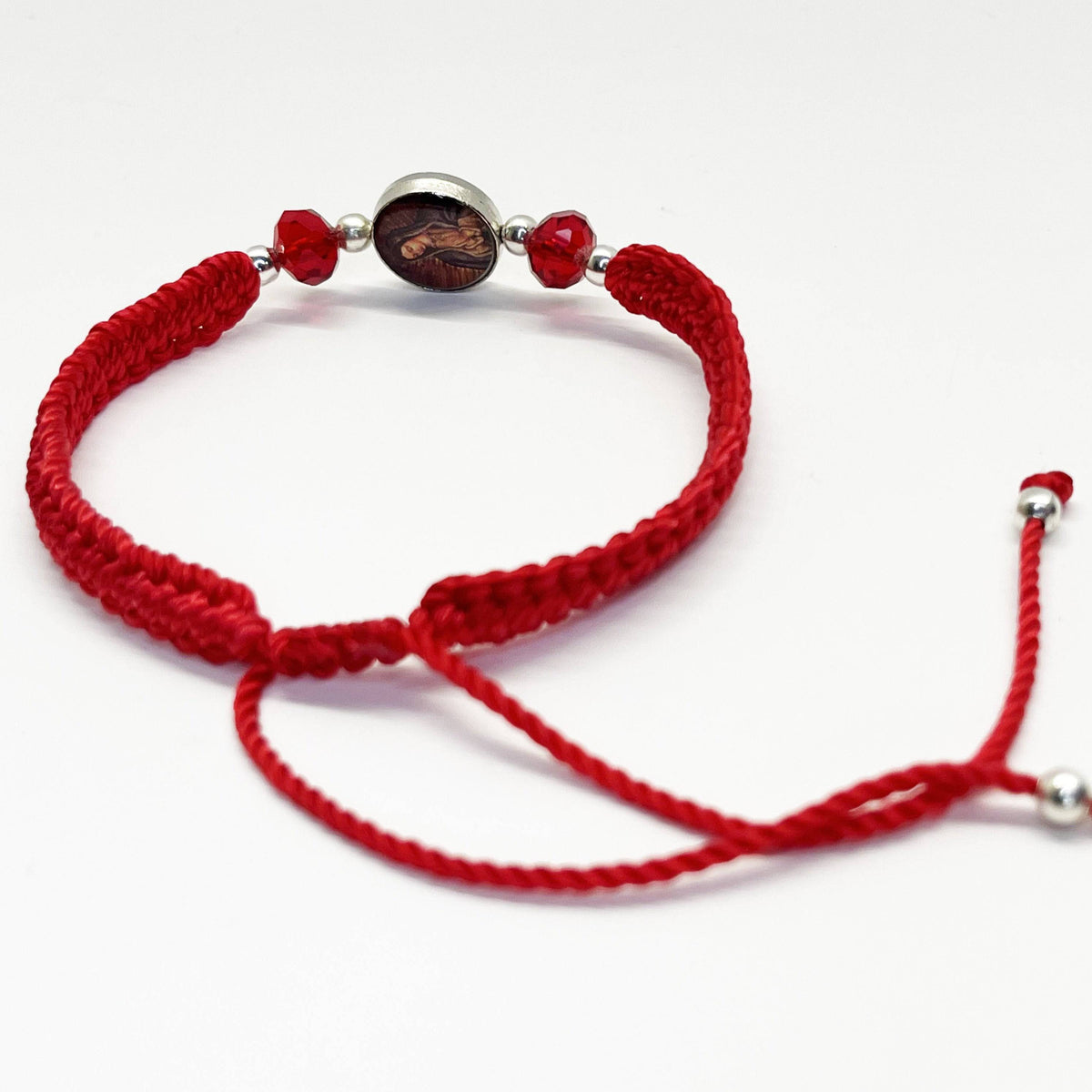 Back view of a adjustable Catholic bracelet in blue nylon thread featuring rhinestones, silver beads, and Guadalupe charm on a white background.
