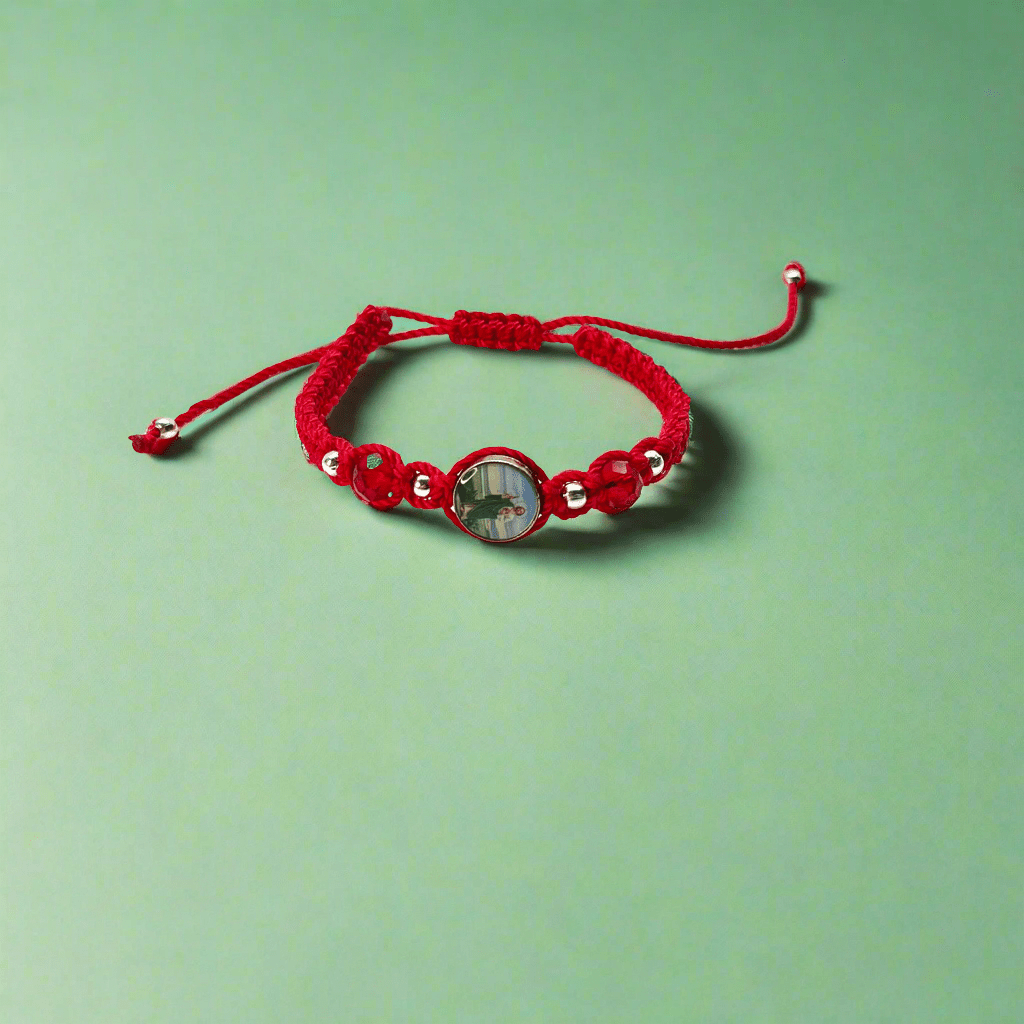 Front view of a handcrafted red nylon St. Jude bracelet featuring silver accents and sparkling red rhinestones on a green background.