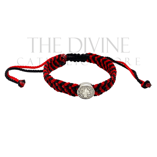 Front view of this handmade red and black woven St. Benedict bracelet with adjustable nylon cord and silver medal charm on a white background.