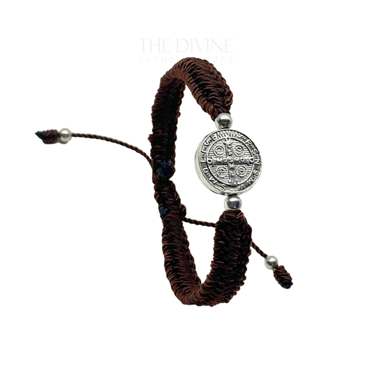 Front view of a adjustable brown nylon St. Benedict bracelet with woven cord and silver medal, durable and lightweight on a white background.