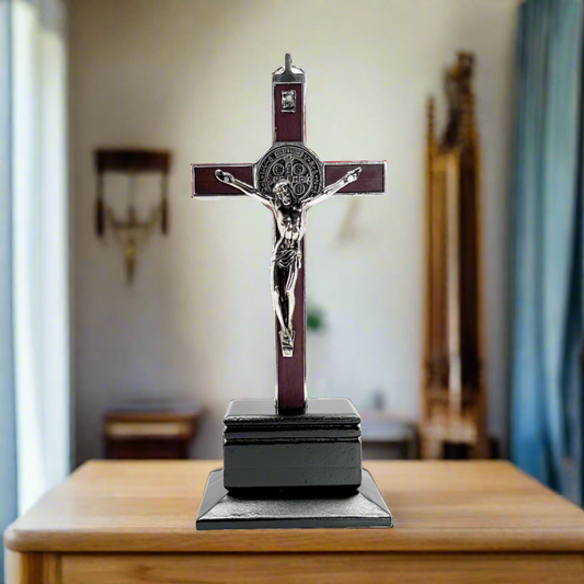 Red 9 Inch St. Benedict crucifix with a figure on a wooden table.