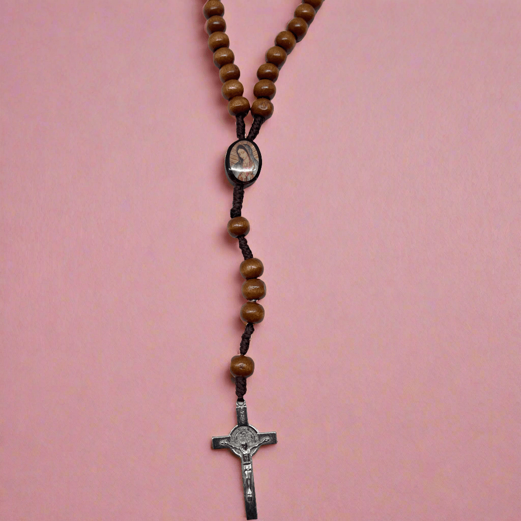 Detailed centerpiece with Our Lady of Guadalupe image on wooden rosary, lacquered beads for prayer on a pink background.