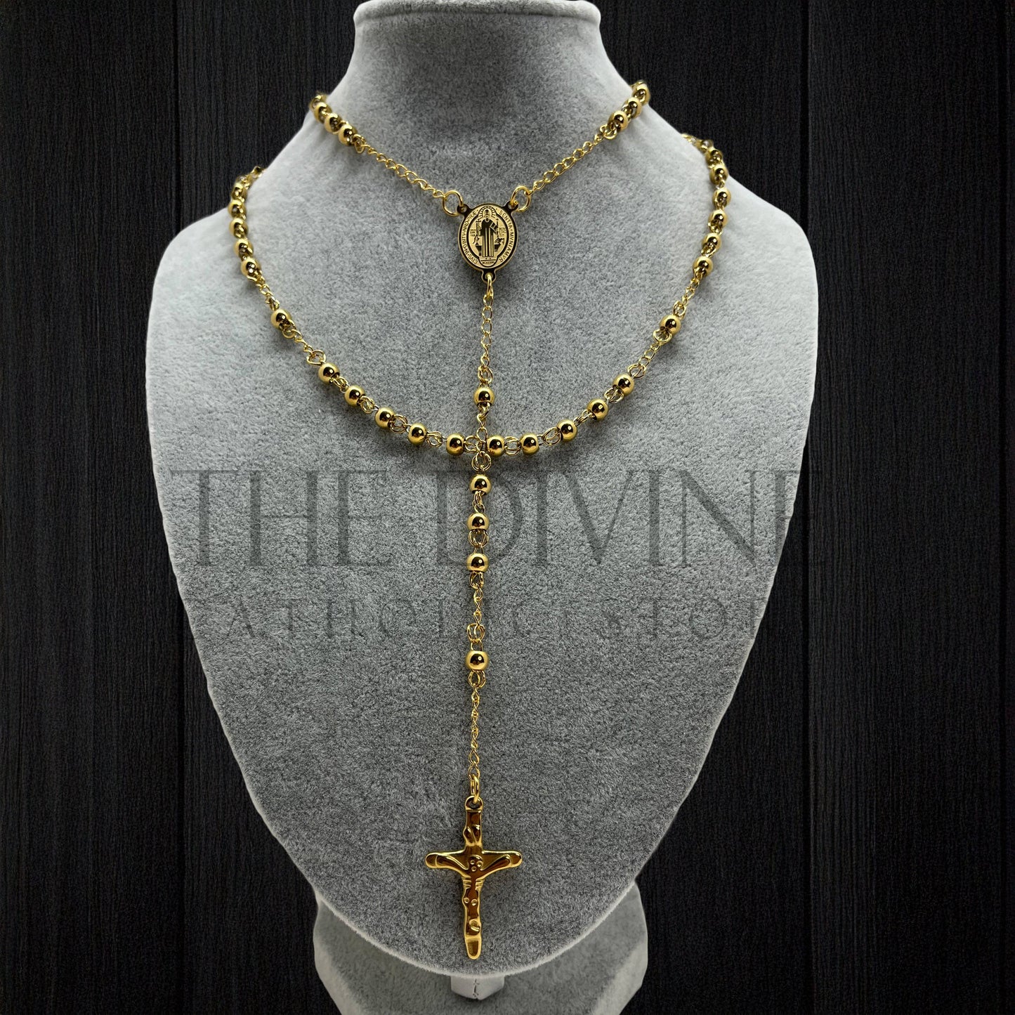 Stainless steel rosary with St. Benedict medal presented on gray bust with black background.