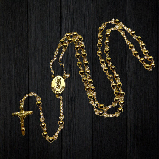 Gold colored stainless steel rosary with St. Jude medal centerpiece and crucifix on a black background.
