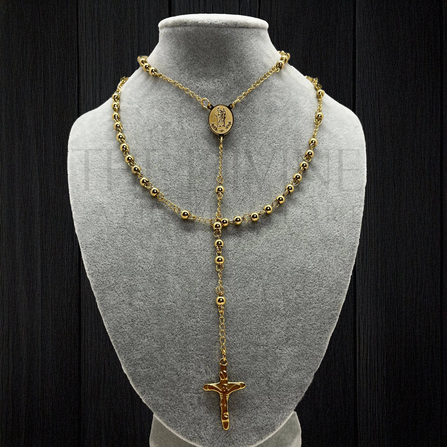 Stainless steel rosary with St. Jude medal presented on gray bust with black background.