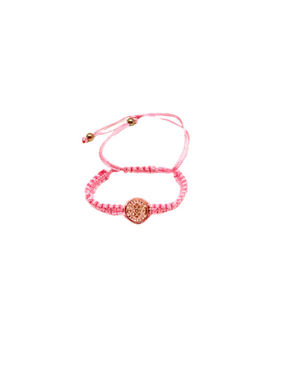 Pink St. Benedict baby bracelet braided bracelet with a circular St. Benedict medal charm on a white background.