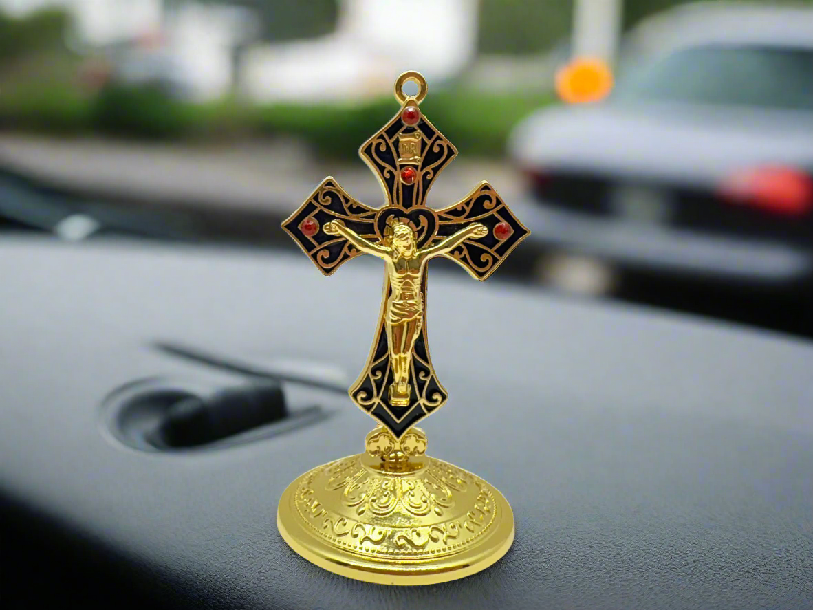 Saint Benedict dashboard crucifix in gold with rhinestones, placed on car dashboard for Catholic protection with
a  blurred background. 