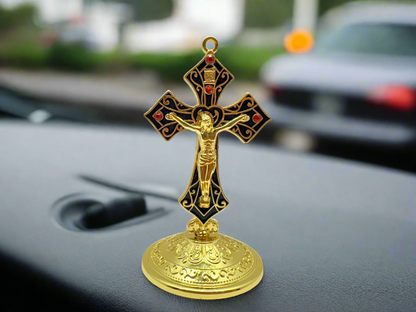 Saint Benedict dashboard crucifix in gold with rhinestones, placed on car dashboard for Catholic protection with
a  blurred background. 