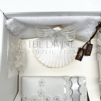 Close up image of the 6 piece baptism candle set showing white candle, shell with white ribbon, white crystal beaded rosary, and bible covered in fabric with nylon thread embroidered, and scapular with Divine Mercy and Our Lady of Guadalupe image, and fabric towel. 