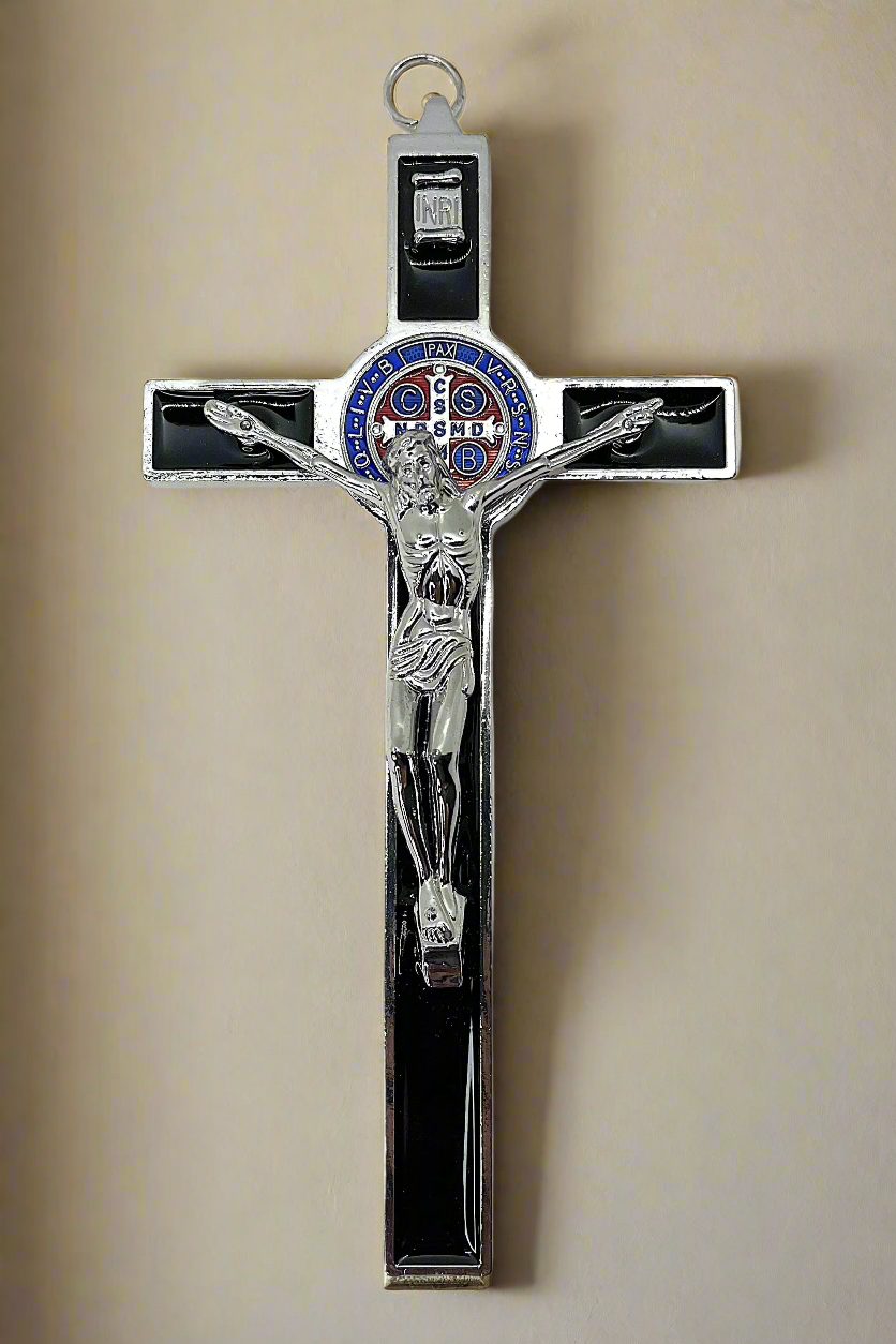 Decorative St. Benedict Crucifix with Black Enamel, blue, red and silver St. Benedict medal, silver corpus Cristi  with silver and blue details on a beige  wall background 