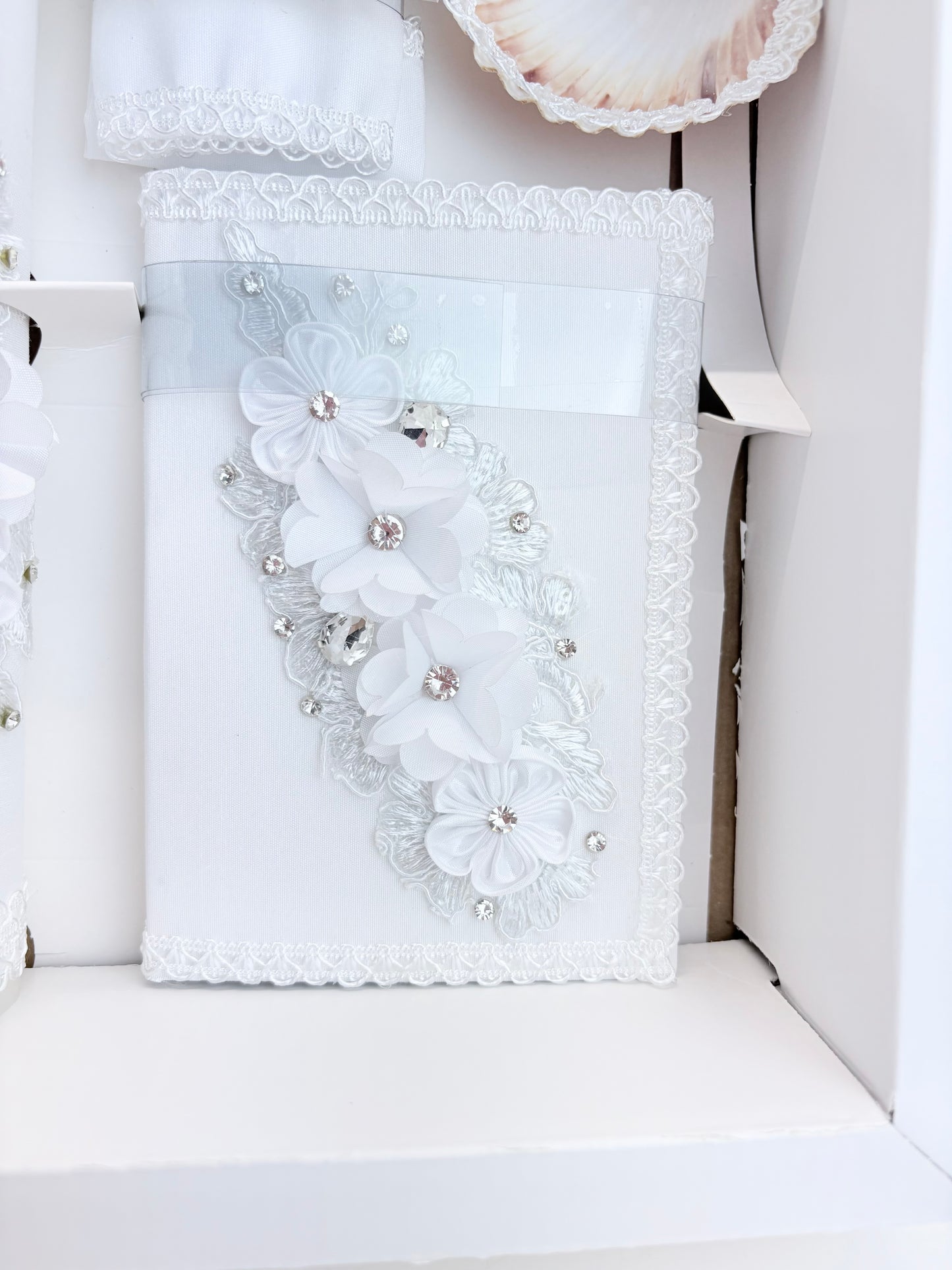 White baptism bible with cascading chiffon flower arrangement rhinestone accents and white lace trim detail