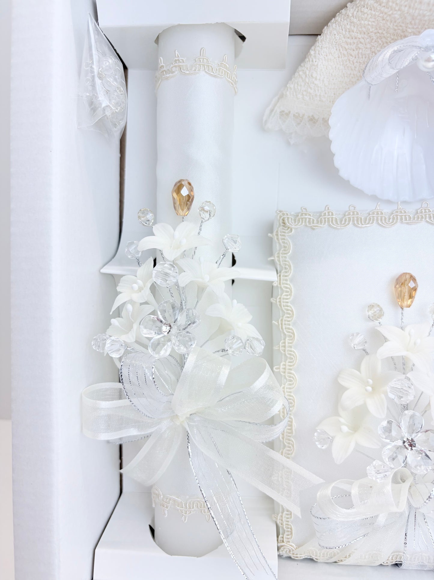 Closeup of ivory baptism candle and bible with matching crystal floral spray gold teardrop accent and organza bow