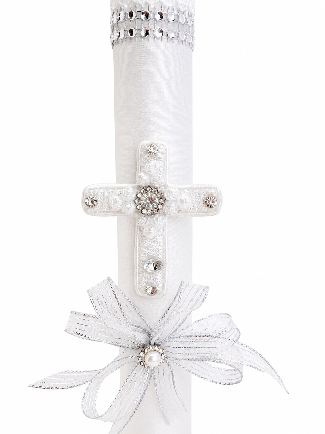 Closeup of white baptism candle with lace rose cross rhinestone cluster center silver organza bow and pearl accent