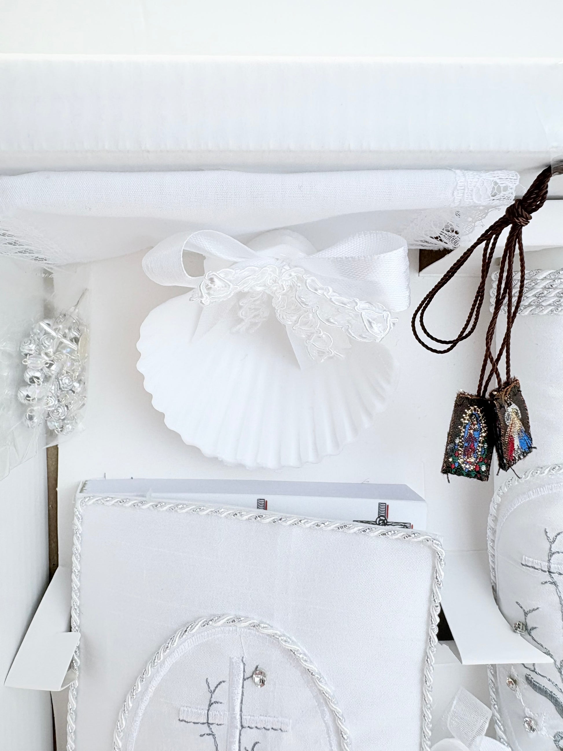 White baptism shell with satin lace bow and divine mercy our lady of guadalupe brown scapular detail