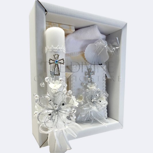 The image features a beautifully designed 5-piece baptism candle set, including a candle, a towel, rosary, bible and a shell. The candle is adorned with white fabric, a braided nylon rope, small white flowers, and rhinestone embellishments, giving it an elegant and sacred look. 