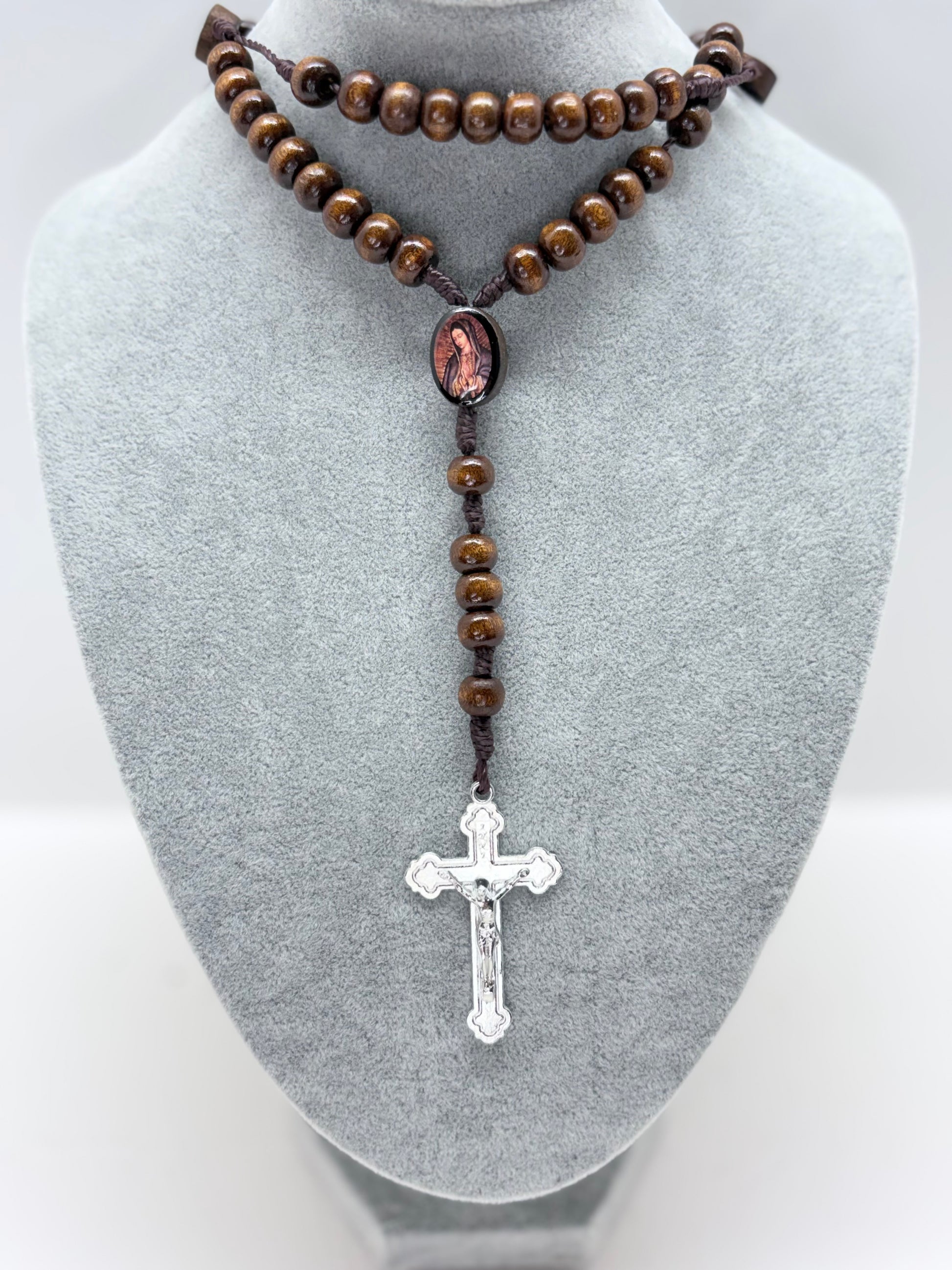 Guadalupe wooden rosary displayed on gray bust with brown wood beads, nylon cord, close-up Our Lady of Guadalupe centerpiece and hanging crucifix