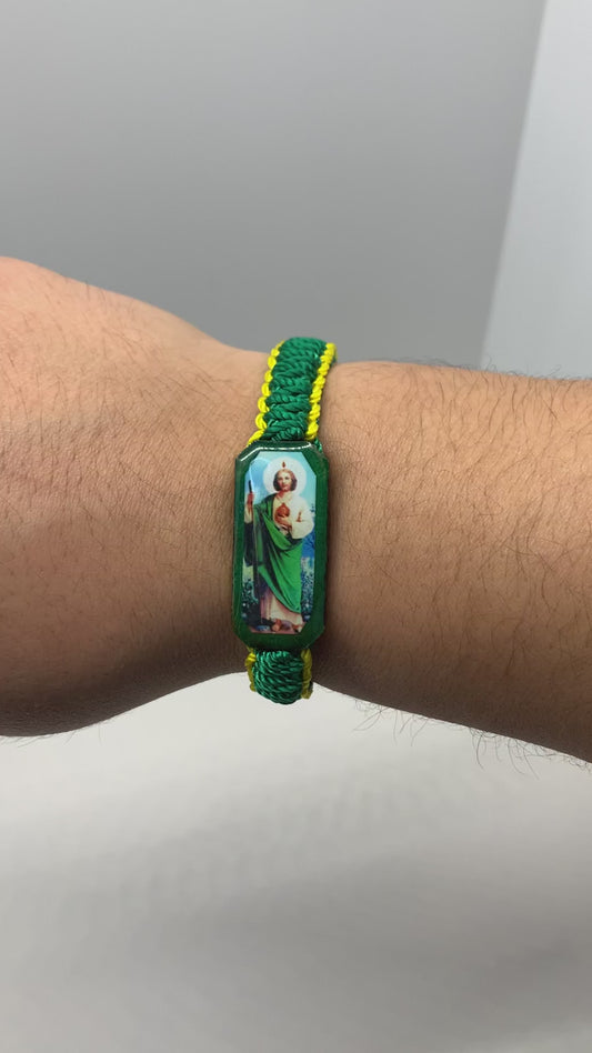 Handcrafted St. Jude bracelet featuring a green cord, yellow bead accents, and a protective St. Jude charm being modeled on a modeled wrist.