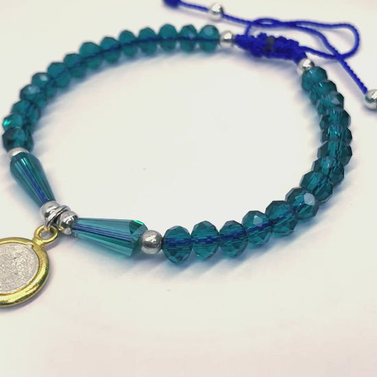 Blue St. Benedict Crystal Beaded Bracelet featuring vibrant blue beads and a silver and gold colored St. Benedict medal, video of bracelet turning to show all sides of bracelet. 