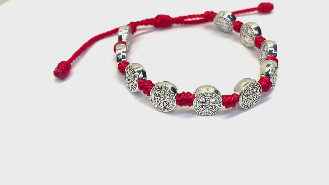 Video of a of a St. Benedict 10 Medal red cord bracelet with oxidized silver accents, adjustable size on a white background.