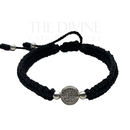 Front view of a adjustable black nylon St. Benedict bracelet with woven cord and silver medal, durable and lightweight on a white background. 