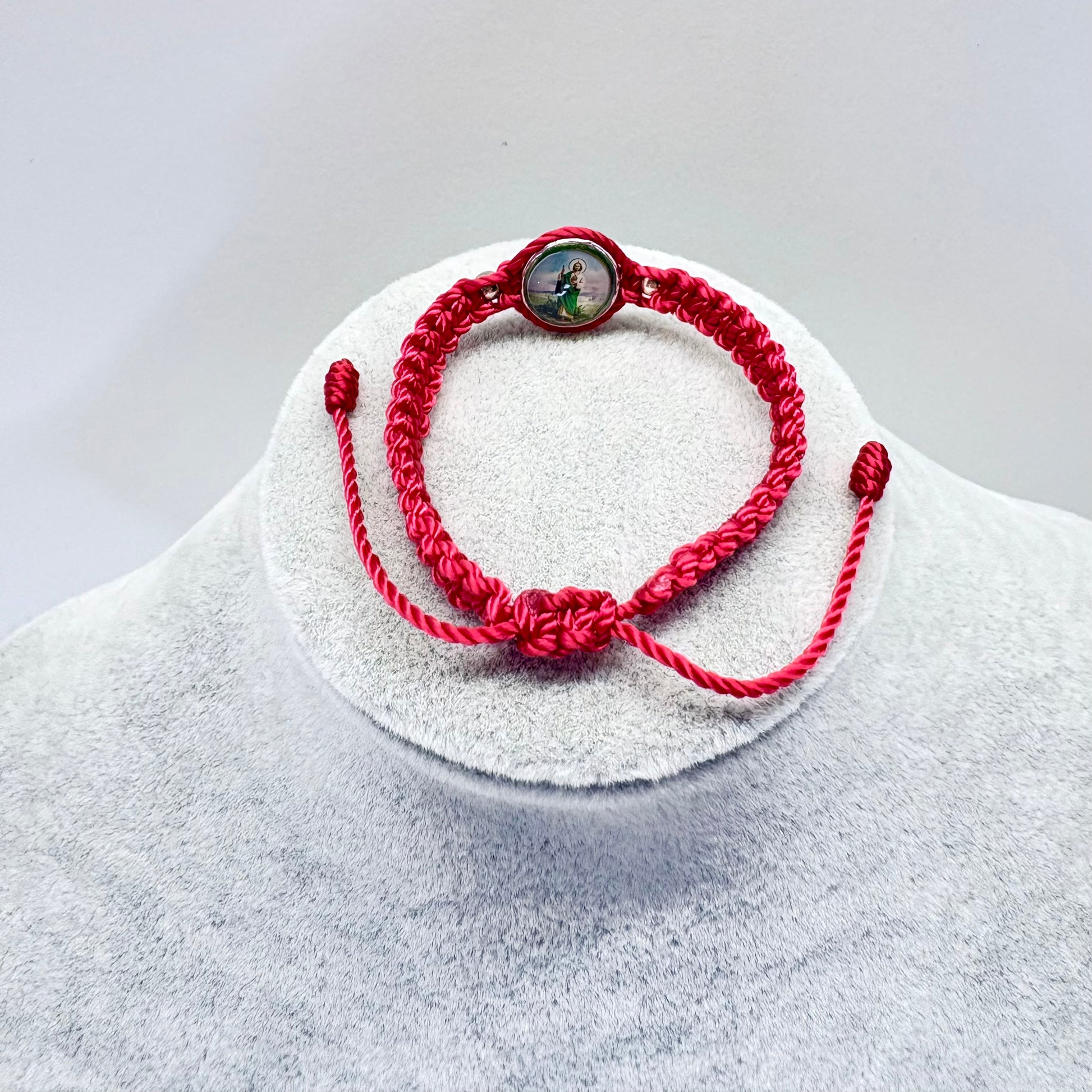 Back view of red St. Jude bracelet showing adjustable knot closure and woven cord detail on display stand