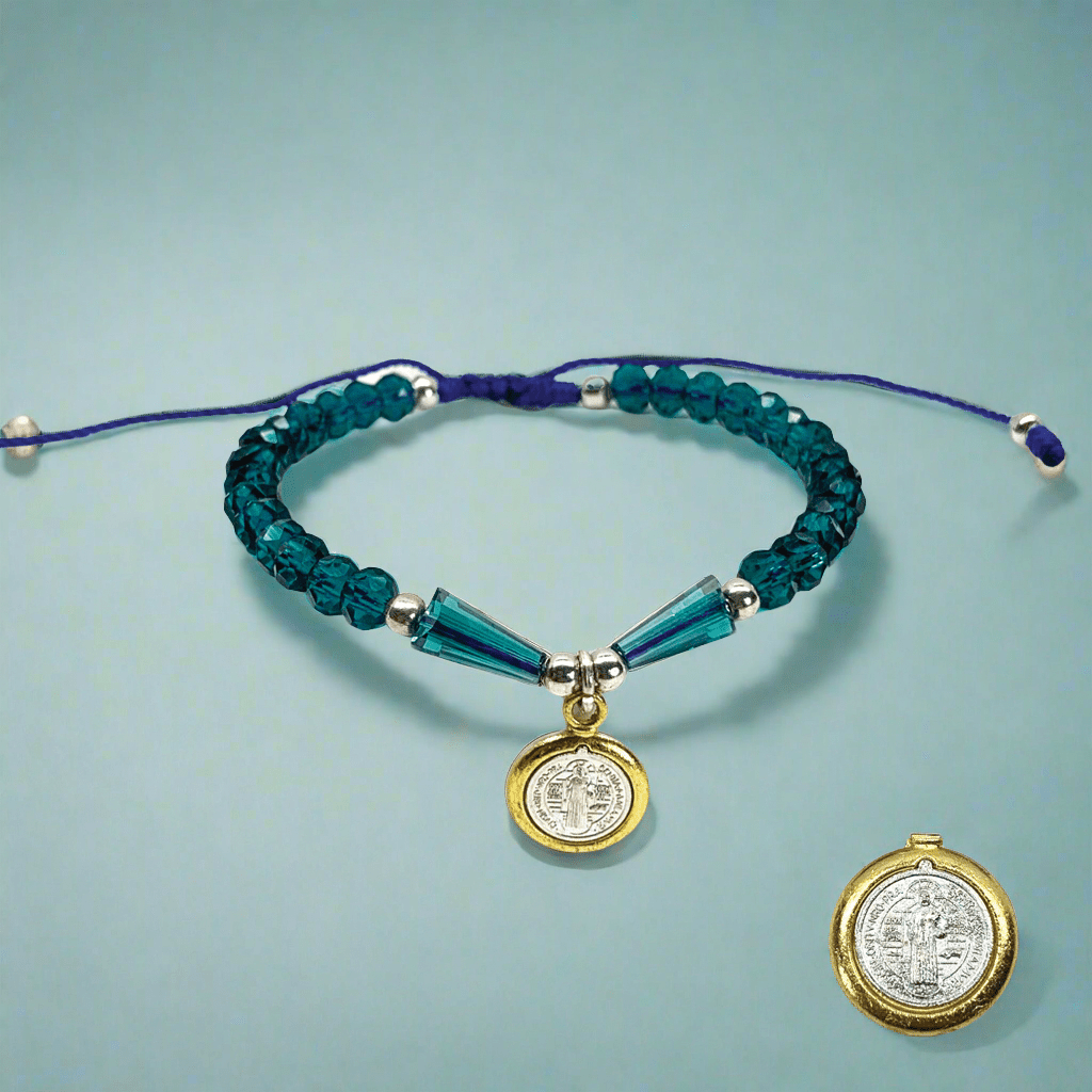 Front view of a St. Benedict beaded bracelet with silver beads and blue, black, or white rhinestones, adjustable Catholic jewelry on a blue background. 