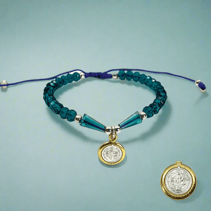 Front view of a St. Benedict beaded bracelet with silver beads and blue, black, or white rhinestones, adjustable Catholic jewelry on a blue background. 