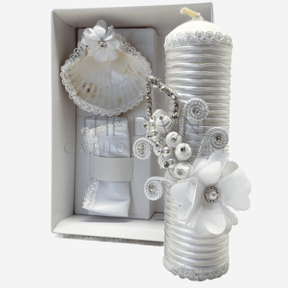 The image features a beautifully designed 3-piece baptism candle set, including a candle, a towel, and a shell. The candle is adorned with white fabric, a braided nylon rope, small white flowers, and rhinestone embellishments, giving it an elegant and sacred look. The towel and shell complement the set, creating a cohesive design perfect for a baptism ceremony.