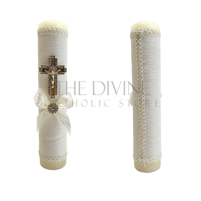 Single ivory baptism candle, decorated with ivory fabric, embroidered with ivory thread, gold colored St. Benedict crucifix outlined in rhinestones, and ivory bow with rhinestone in middle, showing front and back view of candle. 