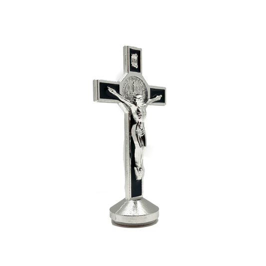 This 3 inch dashboard St. Benedict crucifix is black with a silver St.Benedict medal behind a silver corpus, silver-tone detailing and sturdy base with adhesive at bottom, side view.