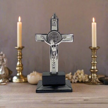Decorative cross with Jesus figure on a stand in front of candles