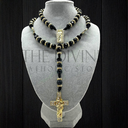 Our Crystal St. Jude rosary in black on a velvet gray bust showing details of the black crystal beads, gold colored charms in between, and gold colored St. Jude pendant and cross with rhinestones. 