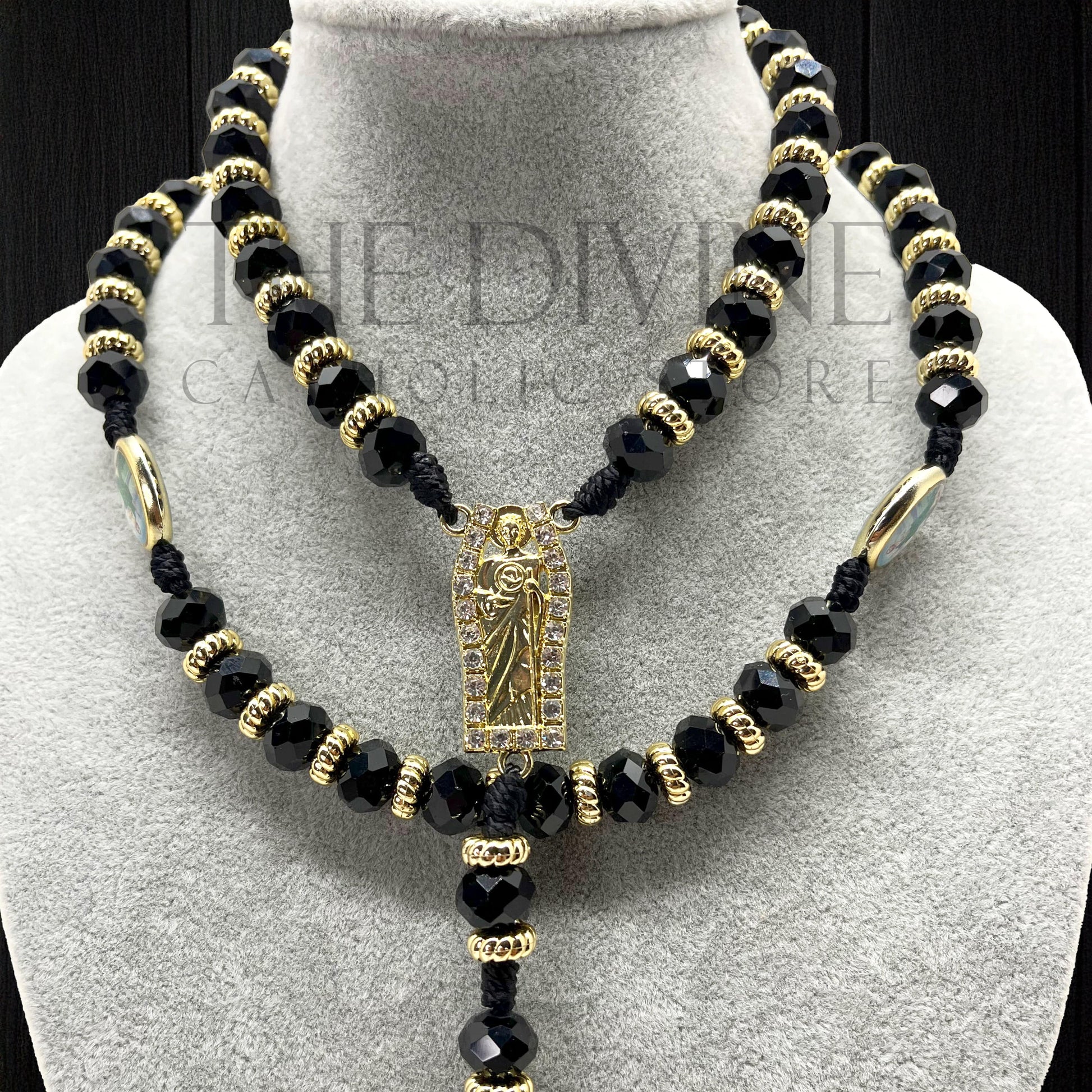 Close up of our crystal St. Jude rosary in black  on a gray velvet bust with black background.