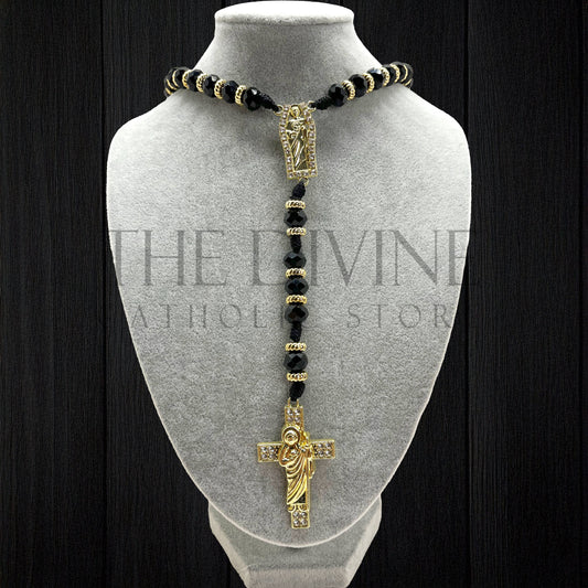 Our crystal St. Jude rosary in black  on a gray velvet bust with black background.