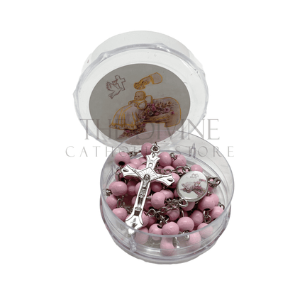 Pink baby girl baptism rosary with crucifix in round clear case featuring a baptism-themed illustration on the lid.